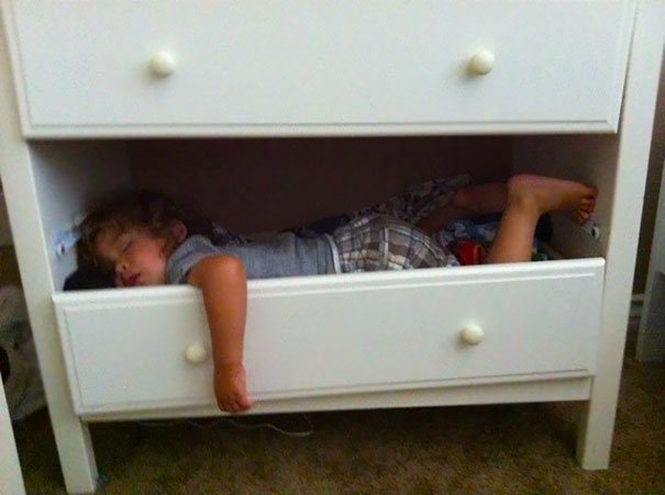 Niño durmiendo dentro de los cajones de una cómoda 