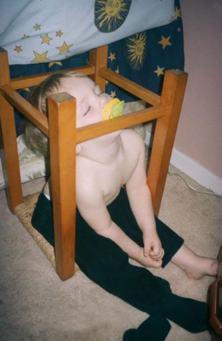 Niño durmiendo sobre una silla volteada 