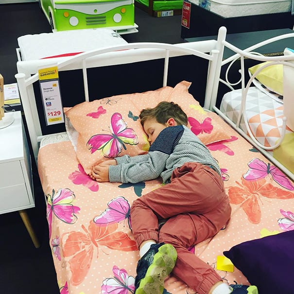 Niño durmiendo sobre una cama de exhibición en una tienda 