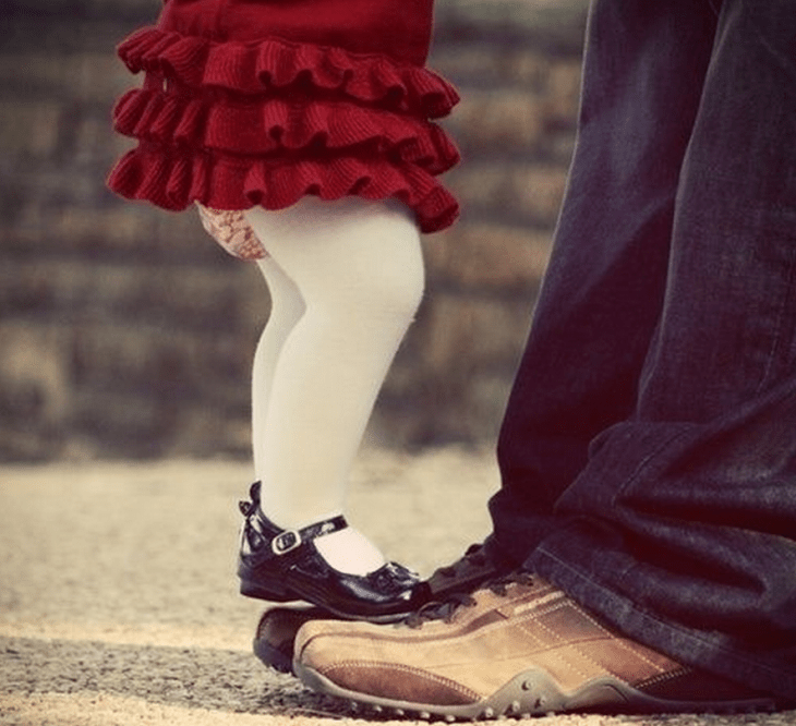 hombre con zapatos cafe y niña con zapatos de charol sobre pies de hombre 