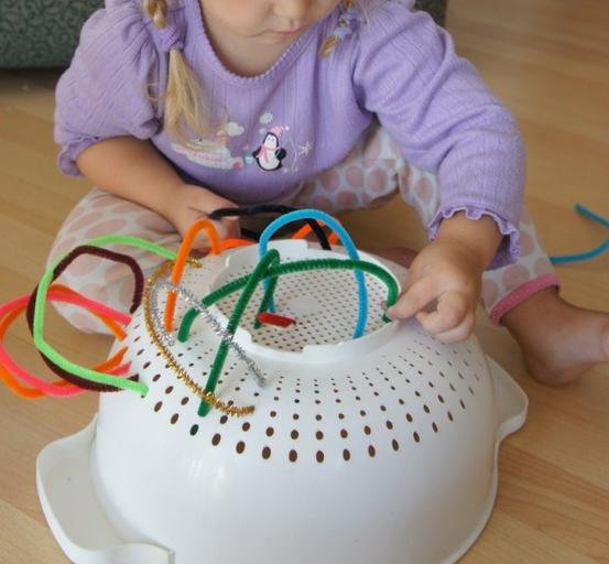 Niña jugando con una colador de cocina. 