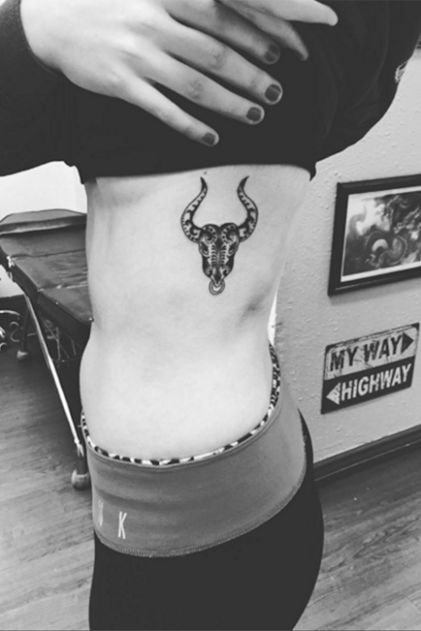 Chica con un tatuaje del signo zodiacal tauro en las costillas 