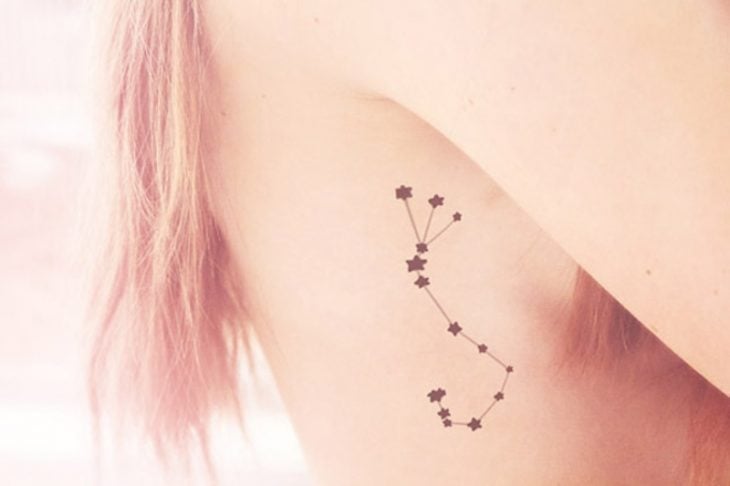 Chica con la constelación de escorio tatuada en sus costillas 