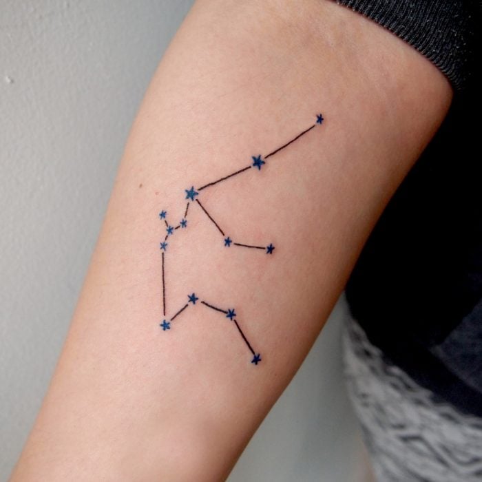 Chica con una constelación de sagitario tatuada en el brazo 