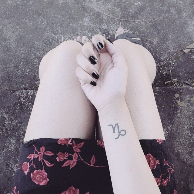 Chica con el signo de capricornio tatuado en la muñeca 