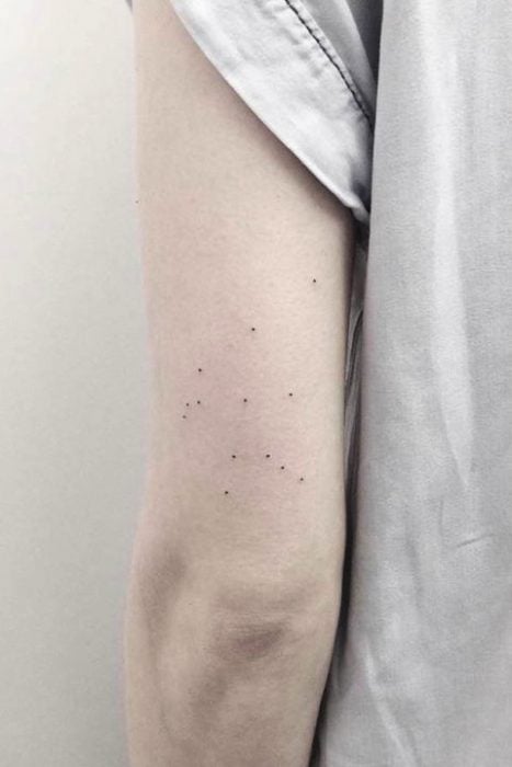 Chica con la constelación de acuario tatuada en el brazo 