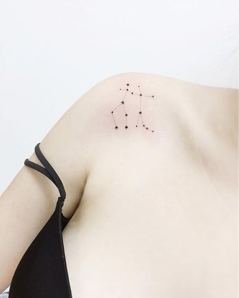 Chica con un tatuaje de la constelación de géminis en el hombro