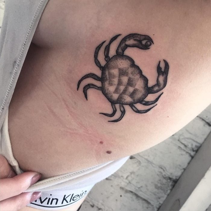 Chica con un cangrejo tatuado en las costillas 