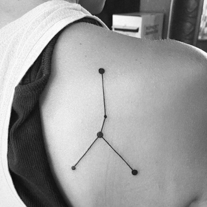 Chica con la constelación de cáncer tatuada en la espalda 