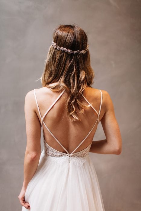 Chica con un vestido de novia con escote en la espalda posando para una sesión de fotos 