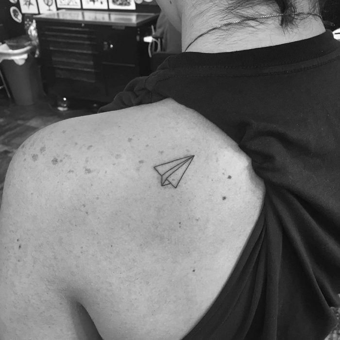 Tatuaje de avión de papel en la espalda. 