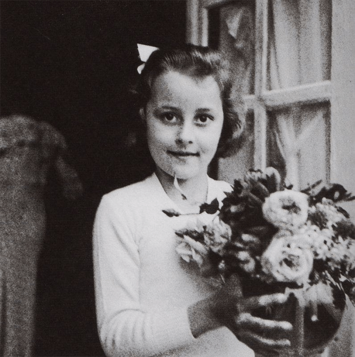 niña con moño y flores en la mano 