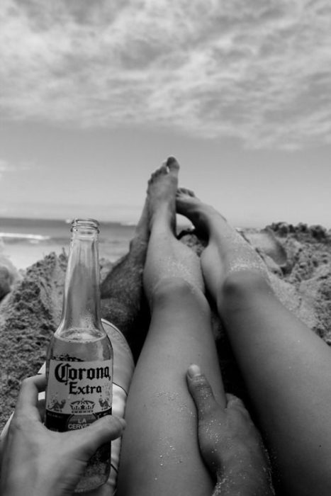 Pareja bebiendo corona en la playa. 