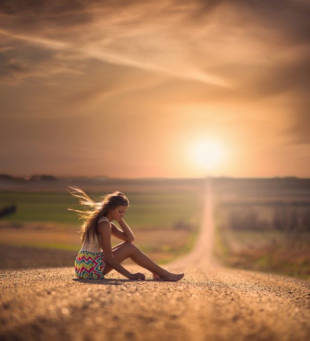 Chica sentada a mitad de la carretera 