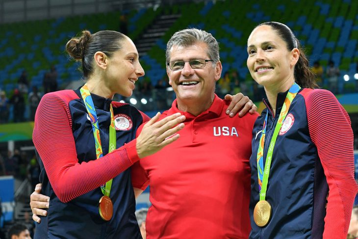 hombre entrenador al lado de dos mujeres con medalla de oro 