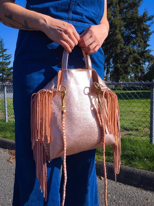 mujer con pantalones azules y bolso rosa gold 