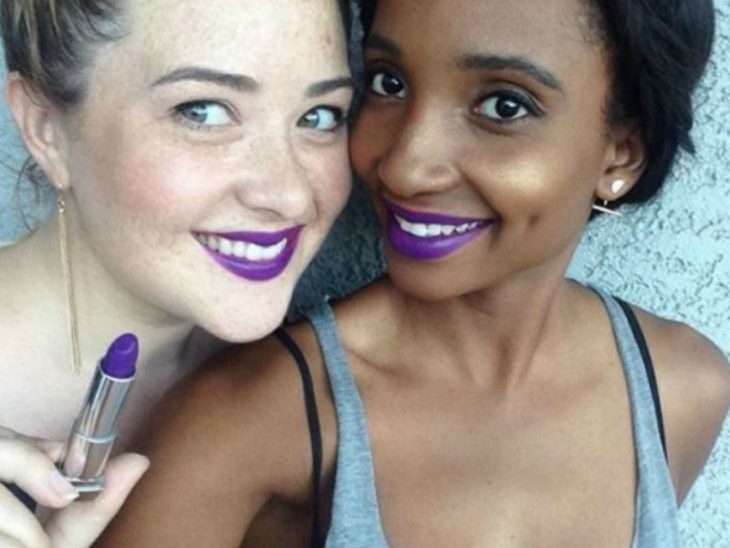 Dos mujeres de piel blanca y morena con labial purpura 