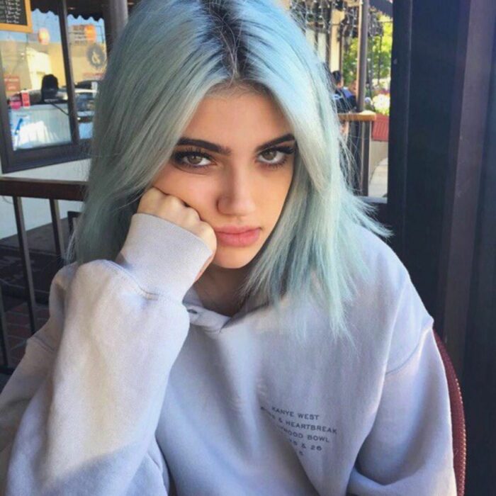 Chica con cara de enojada mientras está sentada tomando un café