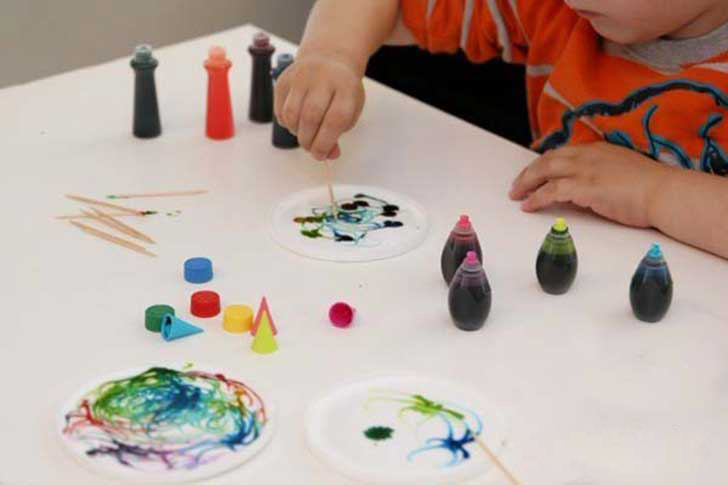 Niños pintando con palillos y pintura vegetal. 