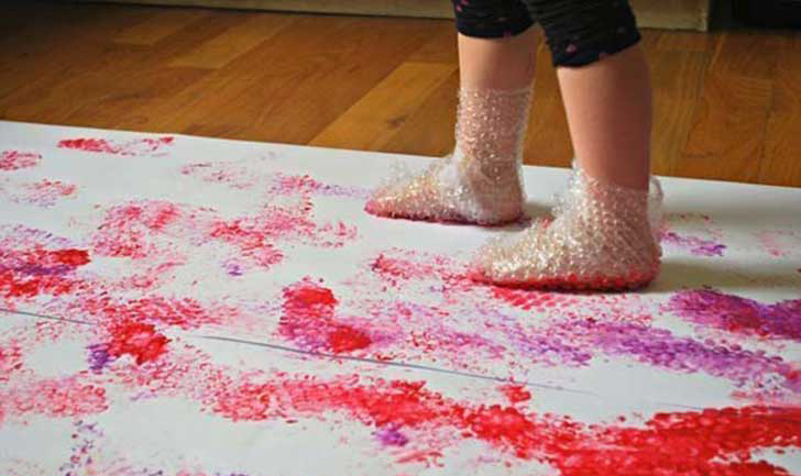 Niña pintando con zapatos hecho con plástico de bolitas. 