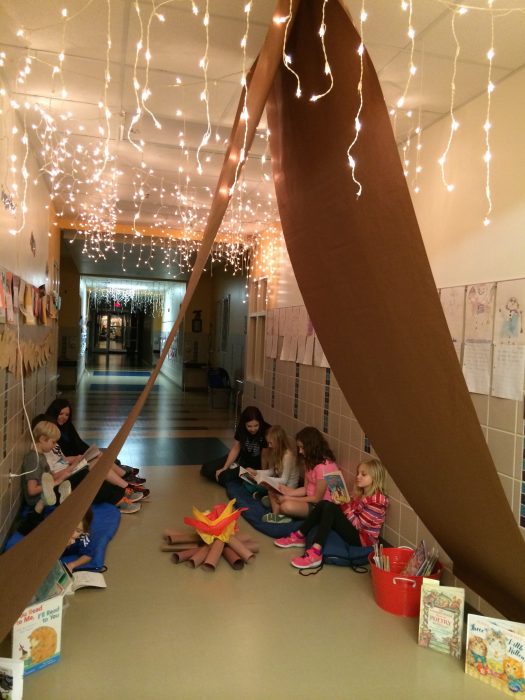 Niños leyendo en un campamento de papel. 