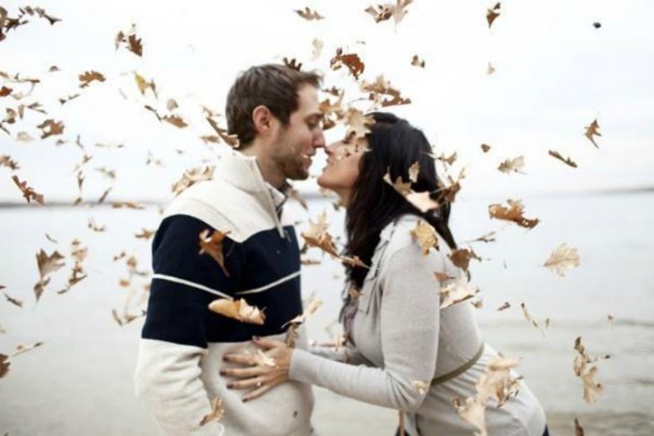 pareja se da besos entre hojas de otoño 