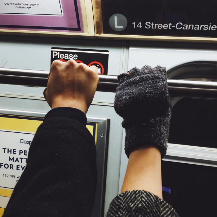 Dos personas agarradas del tubo del metro. 