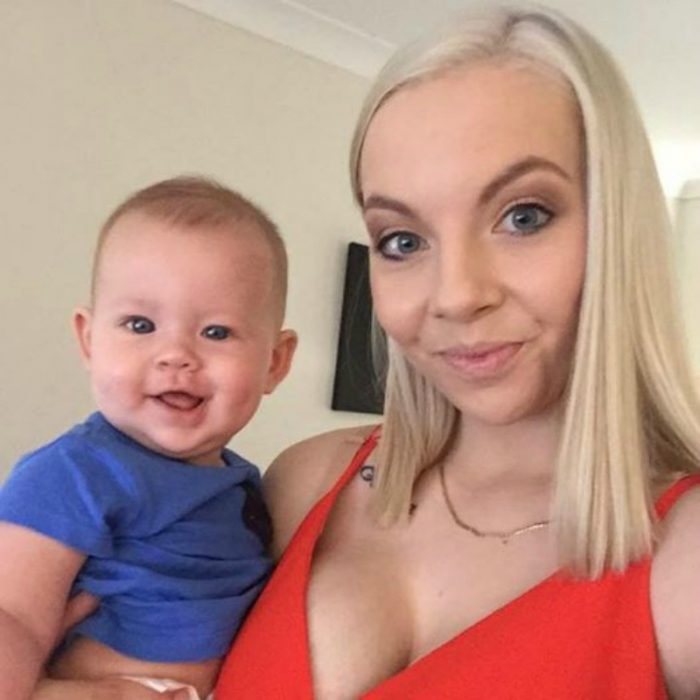 mujer rubia de vestido rojo y bebe con camisa azul 