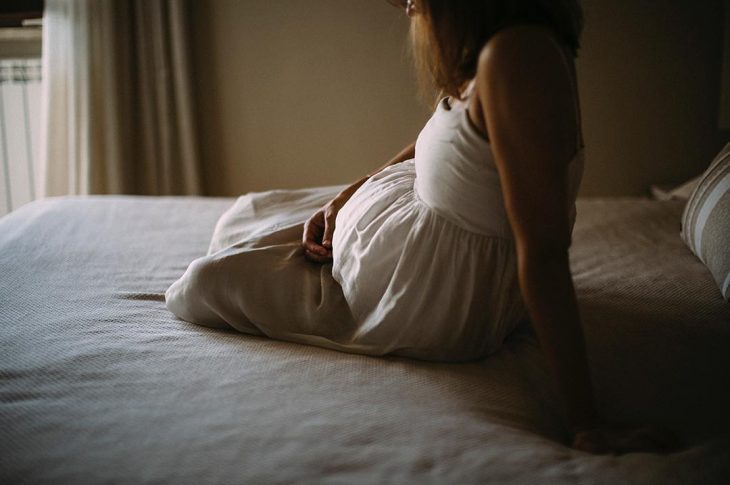 mujer con vestido blanco en cama triste 