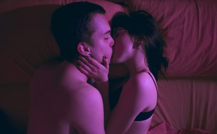 pareja acostada en la cama besándose 
