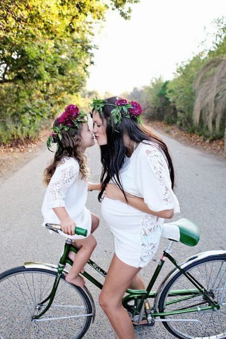 madre e hija con flores en la cabeza en una bicicleta