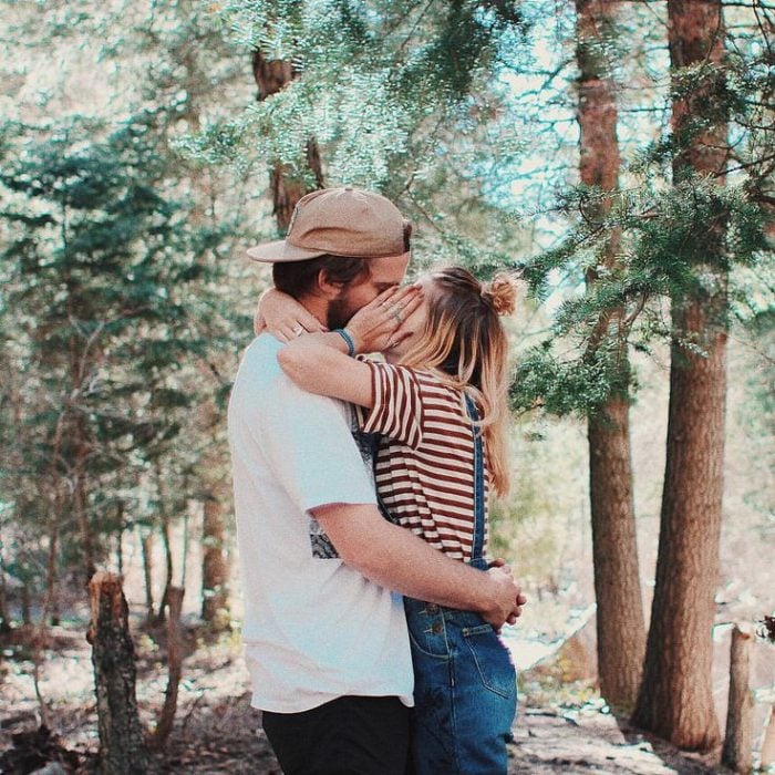 pareja besándose en el bosque 