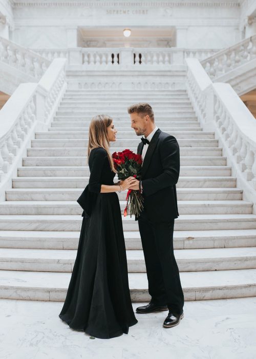 Novio regalando flores a su novia mientras están al final de las escaleras