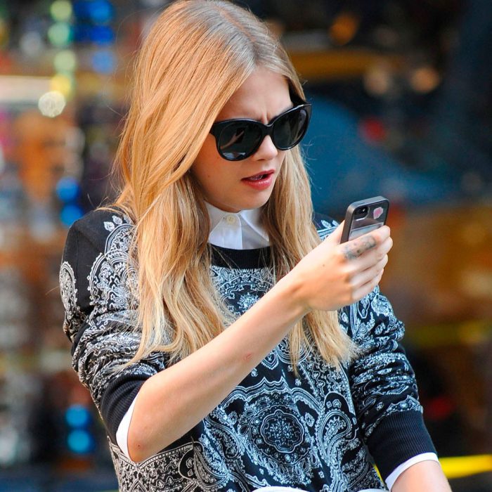 mujer rubia con lentes mirando su celular 