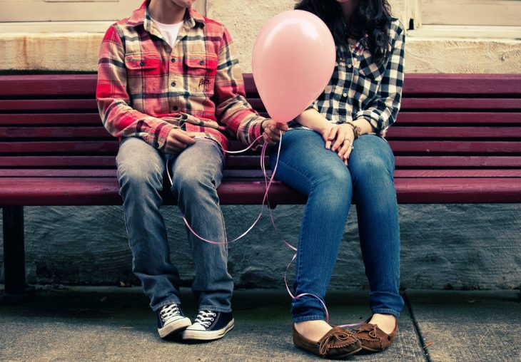 pareja sentada en una banca con un globo