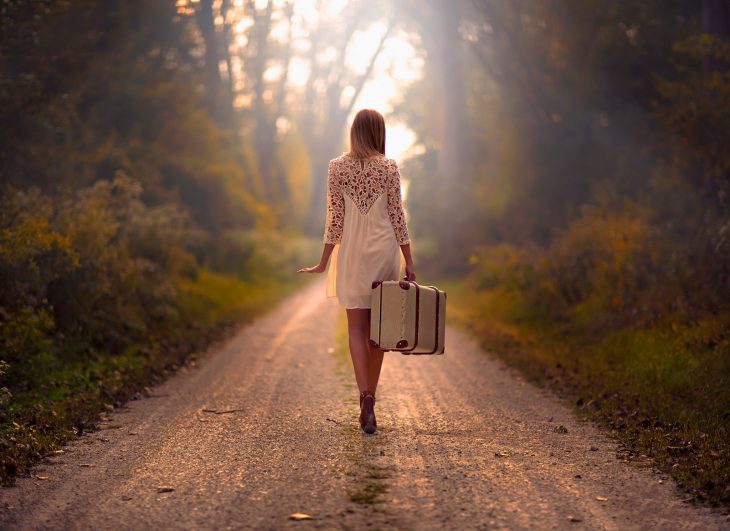 Chica caminando con una maleta en mano 