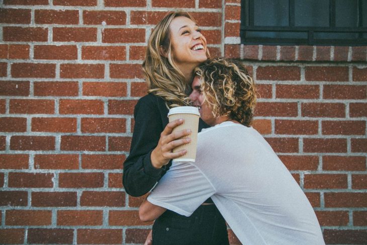 hombre abrazando a chica con cafe 