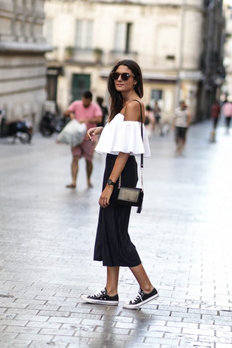 mujer con falda larga, blusa de hombros y tenis converse 