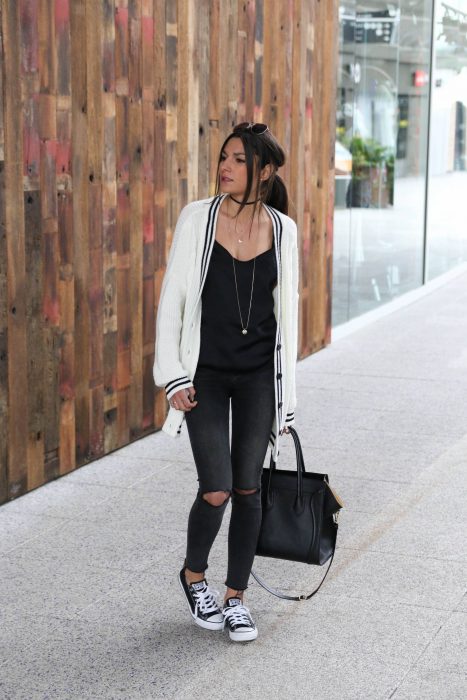 mujer con pantalon negro, sueter blanco y tenis converse 