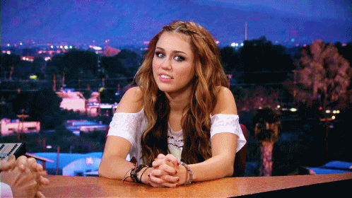 Miley sonriendo falsamente. 