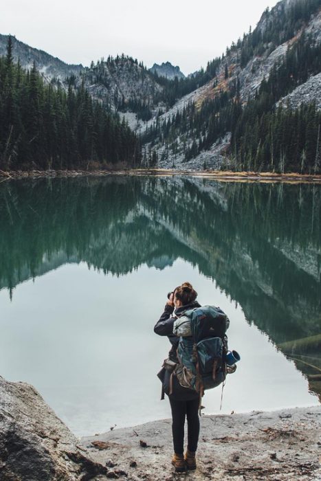 Chica tomando fotos a un lago mientras viaja 