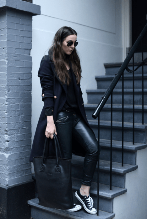 mujer vestida de negro con abrigo negro y tenis converse 