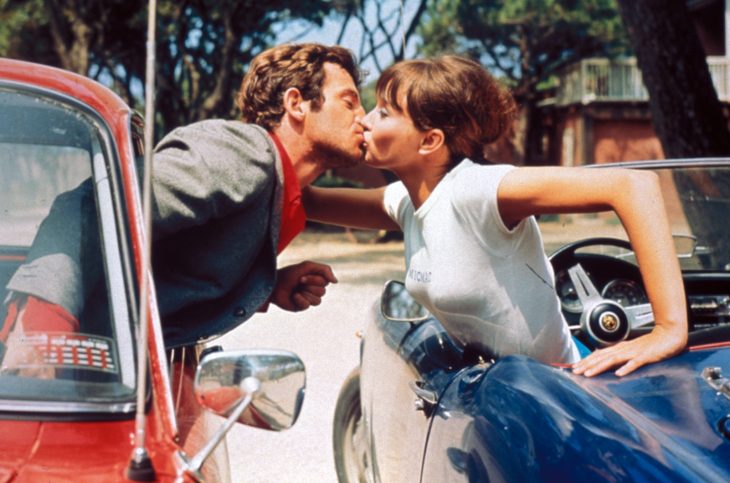 Pareja besándose de carro a carro. 