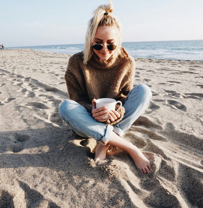 mujer rubia en la playa con lentes 