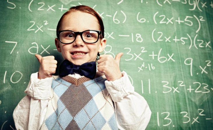 Niño con lentes apuntando al pizarrón. 