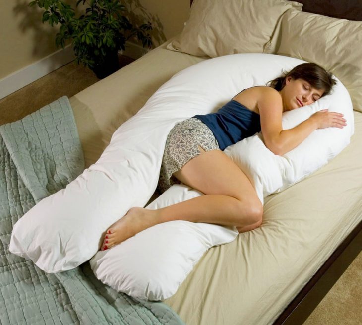 Chica embarazada durmiendo en una almohada en forma de u