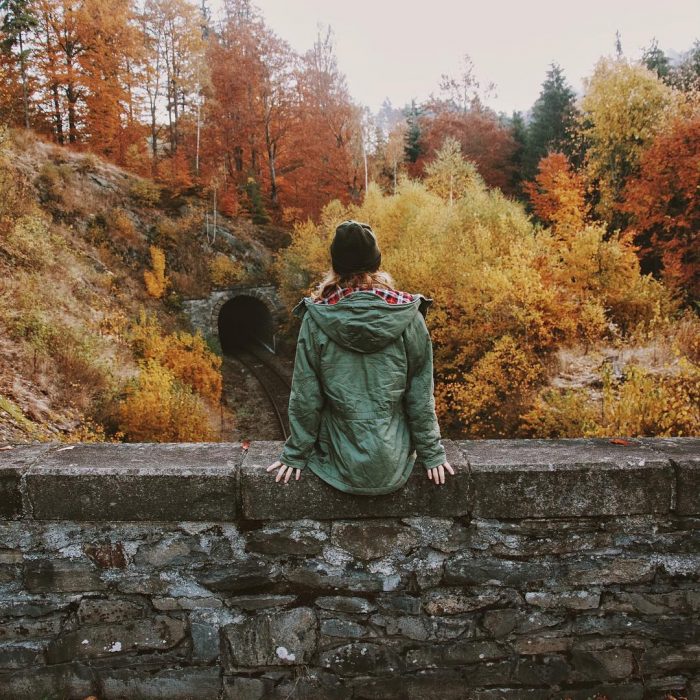 mujer sentada entre arboles en otoño 