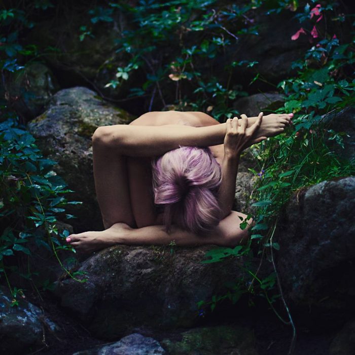 mujer se contorsiona en rocas y naturaleza 