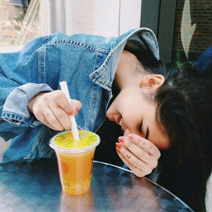 mujer con jugo sonriendo escondida 