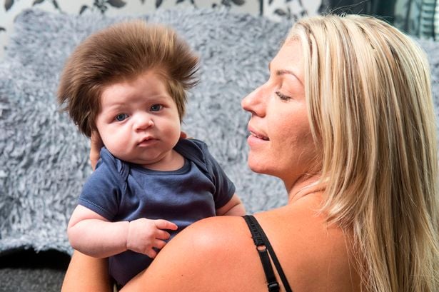 bebé con mucho cabello con su mamá
